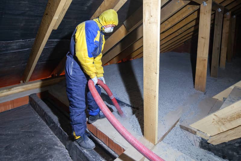 hose spraying white blown-in insulation to area