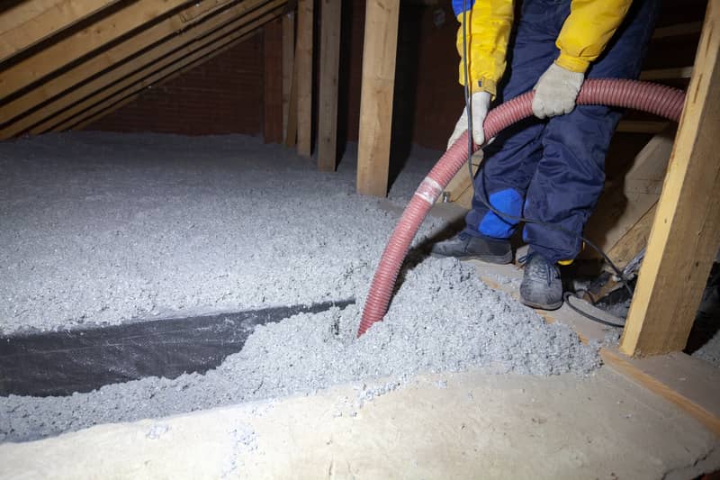 hose spraying white blown-in insulation to area